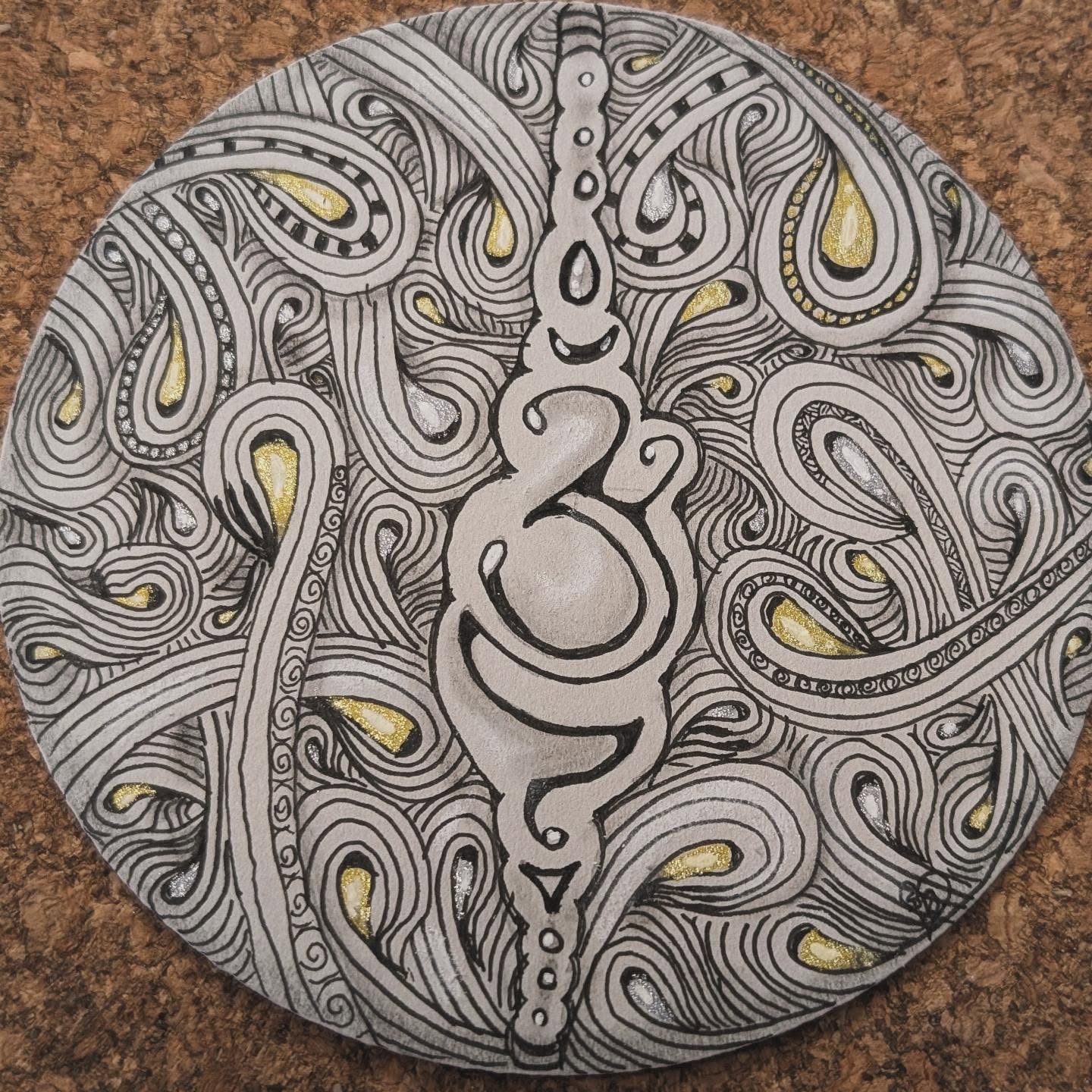 Round hand-drawn Zendala tile with black flowing patterns and gold and silver highlights
