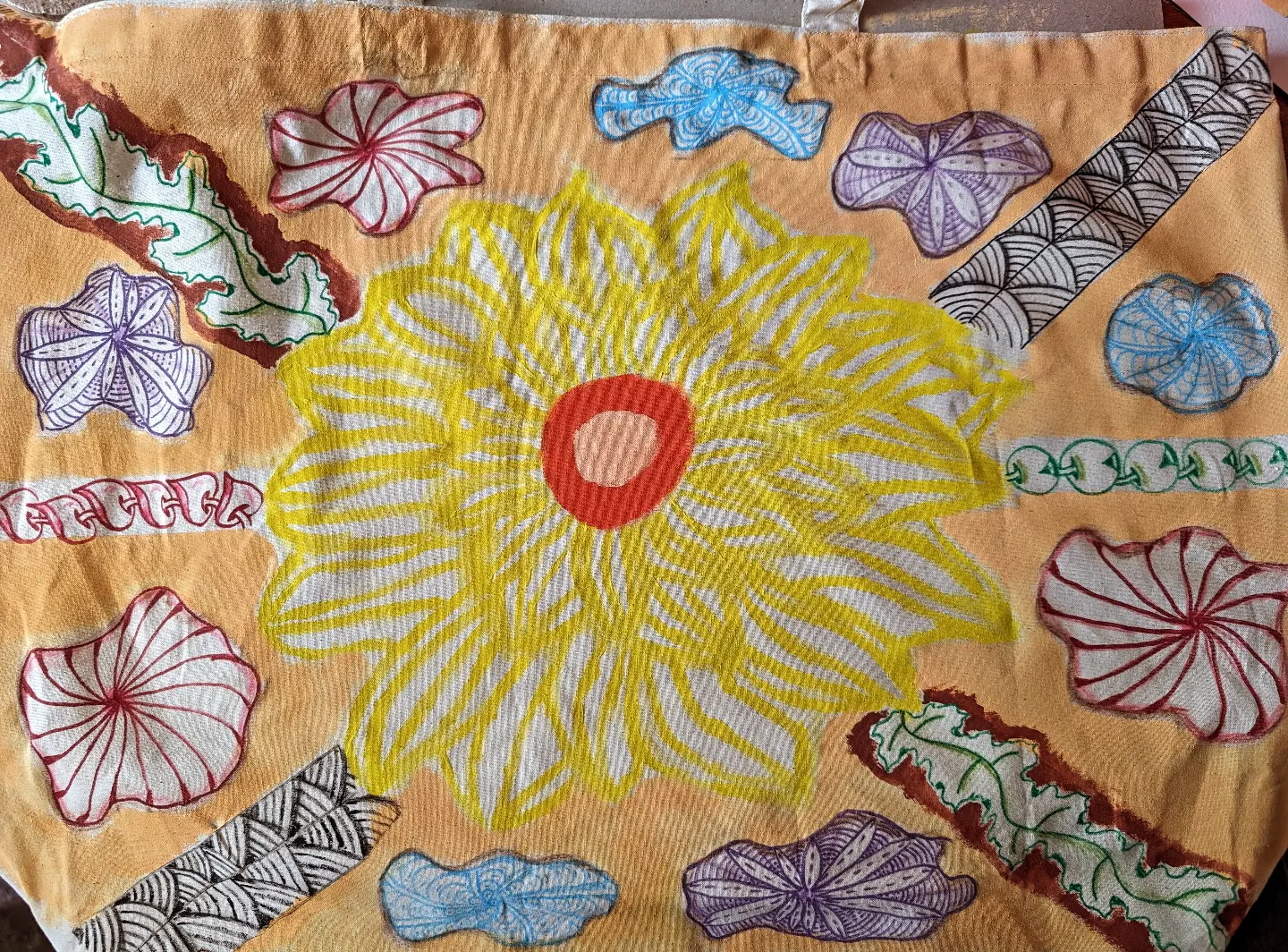 Hand-drawn yellow sunflower surrounded by colourful pattern samples on kraft paper