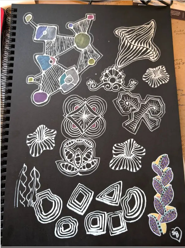 Hand-drawn white Zentangle pattern studies with small coloured details on black paper